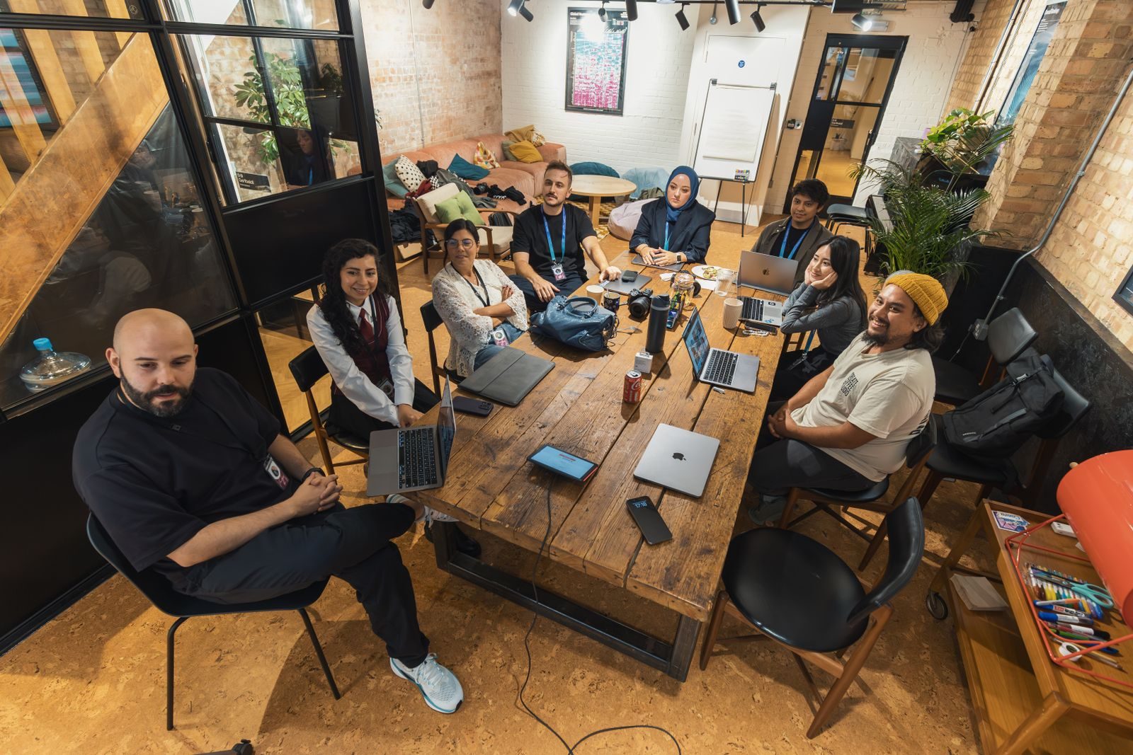 A diverse team collaborating around laptops in a modern workspace